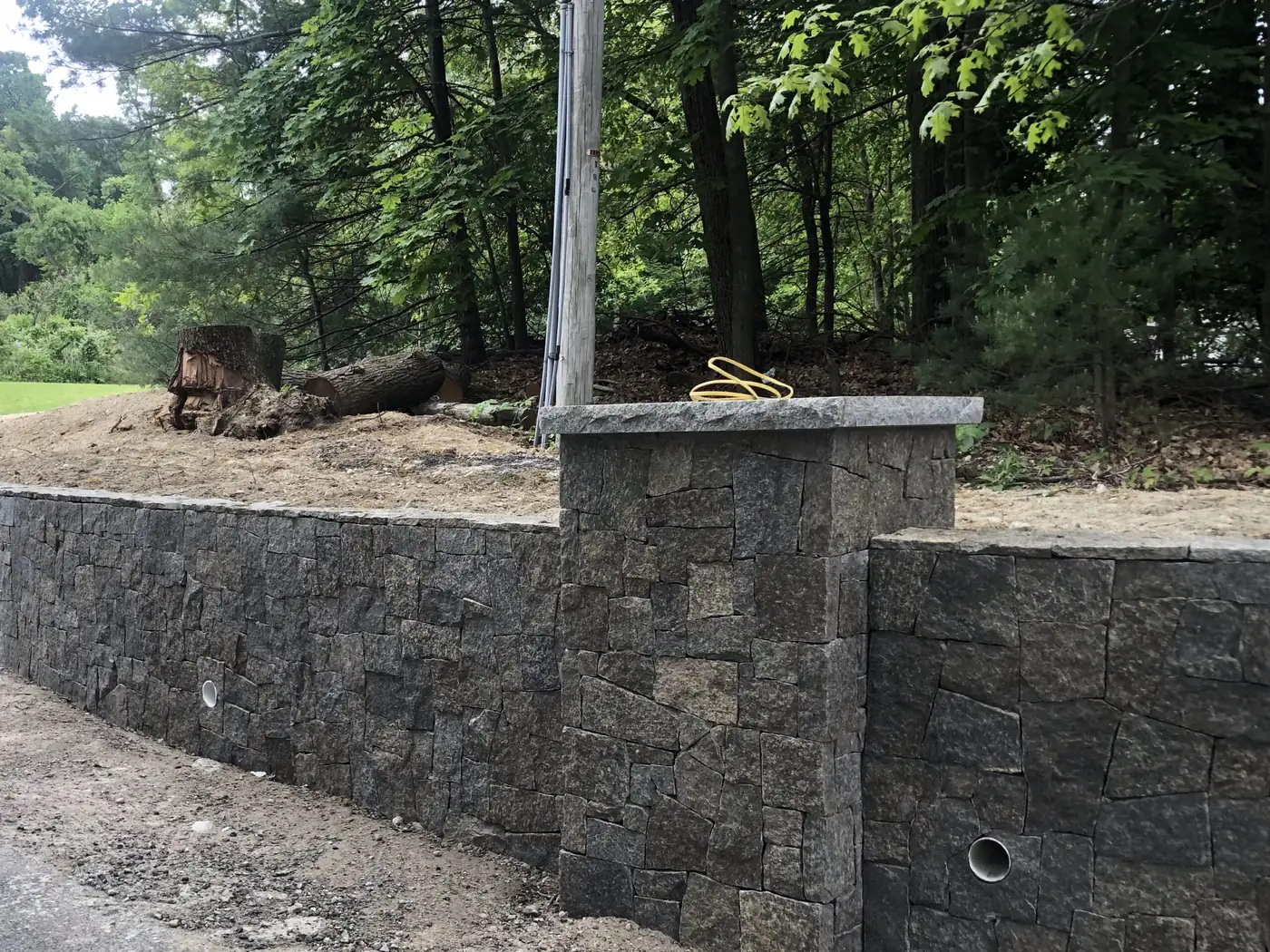 Natural stone wall with a granite cap under construction