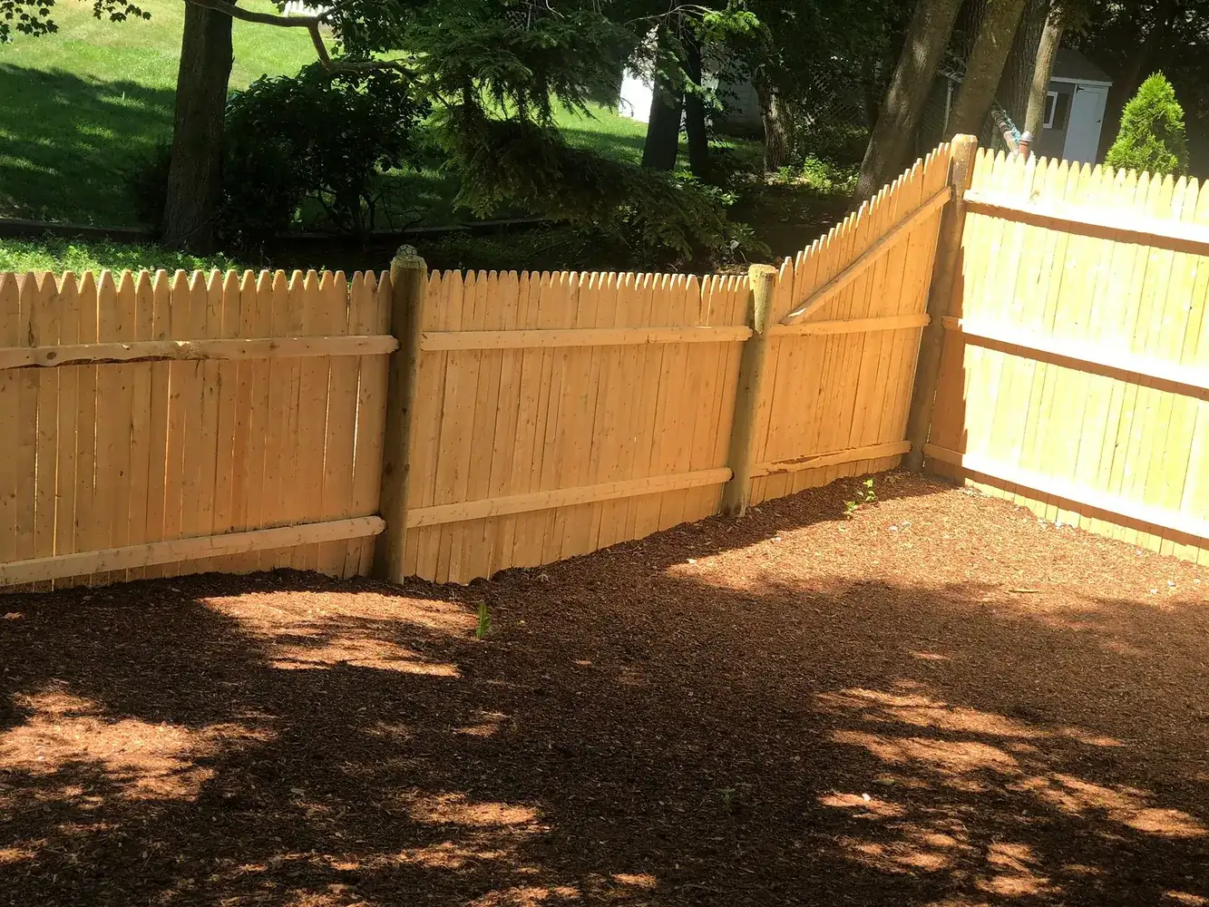 Wood stockade fence with a fresh mulch bed