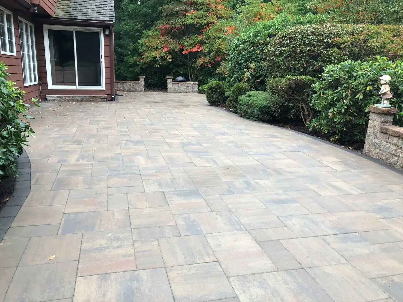 Paver terrace and retaining wall beside a shingled home